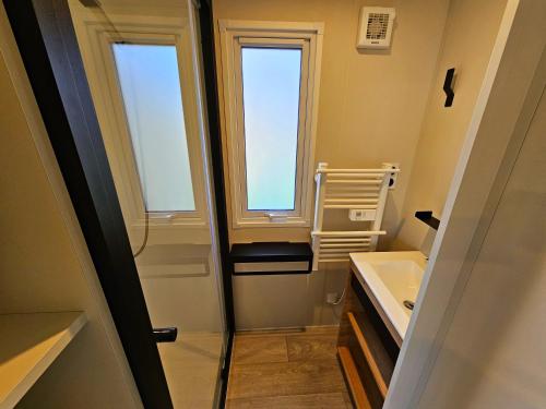 une salle de bain avec un lavabo et deux fenêtres dans l'établissement Camping Les Goélands Carnac, à Plouharnel
