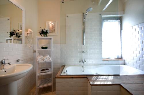 a white bathroom with a tub and a sink at Tenuta Decimo - Villa Dini in San Gimignano