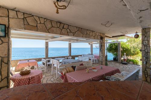 a patio with tables and chairs and the ocean at Vila Dora in Dobra Voda