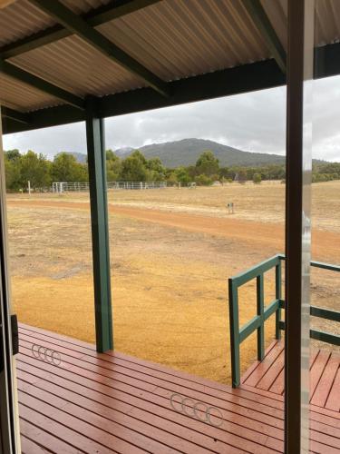a porch with a green bench on a field at Manyat Peak cottages Kestrel in Porongurup