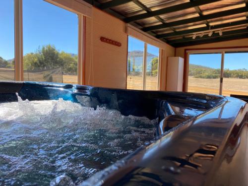 a hot tub with water in a room with windows at Manyat Peak cottages Kestrel in Porongurup