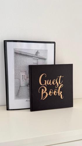 a guest book sitting on a shelf next to a picture at Malvern Hills House in Great Malvern