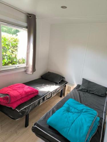 deux lits dans une petite pièce avec une fenêtre dans l'établissement Mobil home, à Gastes