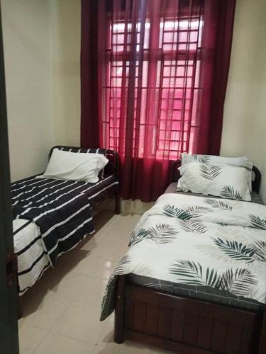 a bedroom with two beds in front of a window at Homestay Taman Pinggiran Universiti in Bachok