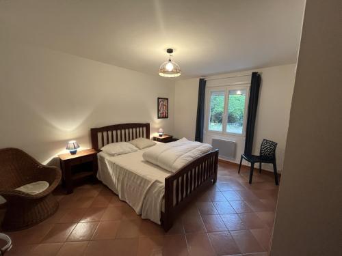 une chambre avec un lit, une chaise et une fenêtre dans l'établissement Maison calme en pleine nature jusqu'à 10 personnes, à Cabrespine