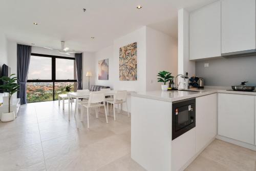 - une cuisine et une salle à manger avec des placards blancs et une table dans l'établissement Lumi Tropicana Golf Course View, à Petaling Jaya