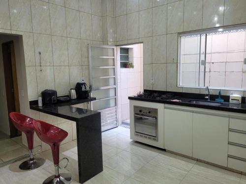 a kitchen with a counter and a red chair in it at Pousada Céu de Viracopos in Campinas