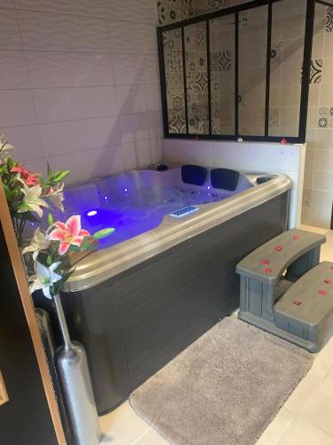 une grande baignoire bleue dans une salle de bain avec une fleur dans l'établissement Suite romantique Au cœur du Spa avec jacuzzi et sauna privatif proche de Toulouse, à Auterive