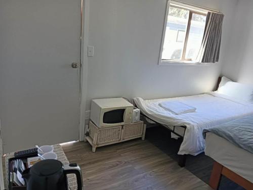 a small room with two beds and a tv at 1 Bedroom garden chalet, 7B Salisbury Road, Rotorua in Rotorua