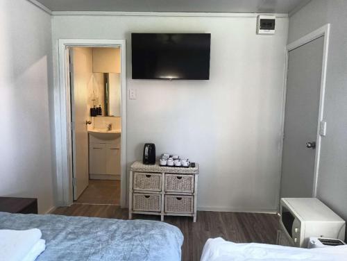 a bedroom with a bed and a television on the wall at 1 Bedroom garden chalet, 7B Salisbury Road, Rotorua in Rotorua