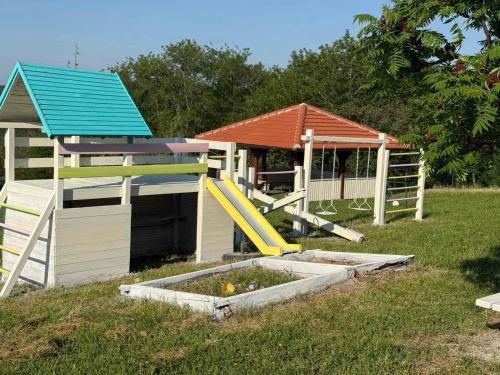 a playground with a play house and a slide at Zen Cherry House- Vikendica na dan sa bazenom1,5ha izmedju Avale i Kosmaja in Drobnjaci