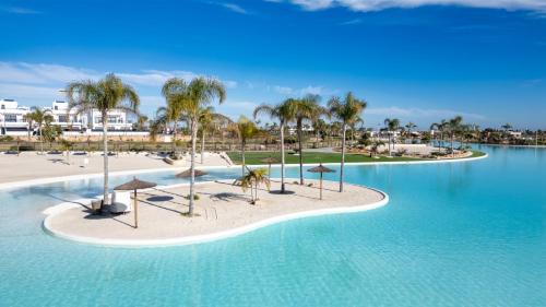 a resort pool with umbrellas and a beach at Santa Rosalía Lake & Life Resort Penthouse in Torre-Pacheco
