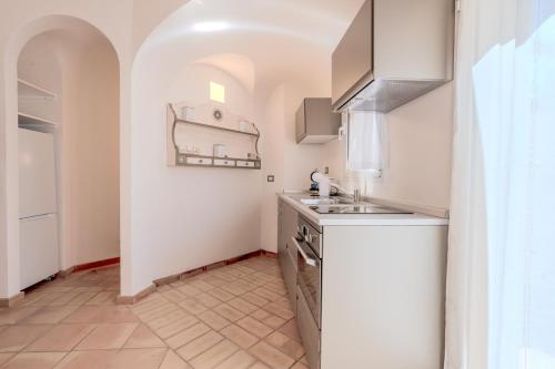 a small kitchen with a sink and a stove at Baja Sardinia - Cala dei Ginepri, Villetta a 80m dalla Spiaggia in Cala Bitta