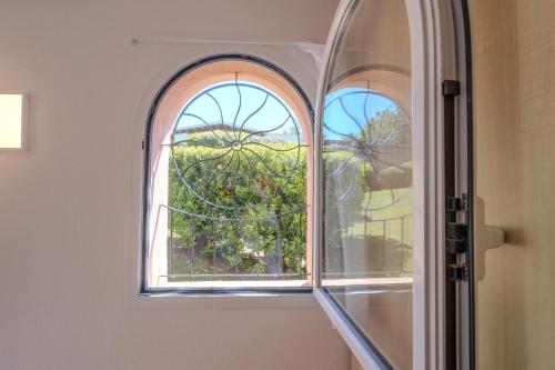 an arched window in a room with a tree at Baja Sardinia - Cala dei Ginepri, Villetta a 80m dalla Spiaggia in Cala Bitta