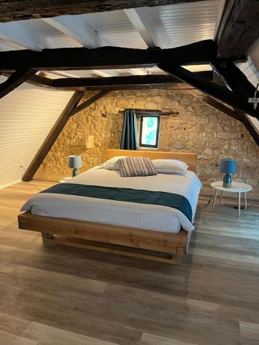 une chambre avec un grand lit dans un mur de pierre dans l'établissement Maison Périgourdine près de Bergerac avec Spa privé, à Monsac