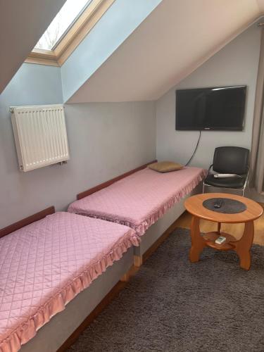 two beds in a room with a table and a tv at Marta in Okuninka