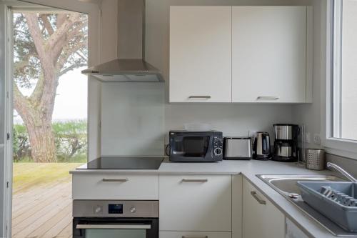 une cuisine avec un évier et un micro-ondes dans l'établissement Villa Germaine les pieds dans l'eau, à Andernos-les-Bains