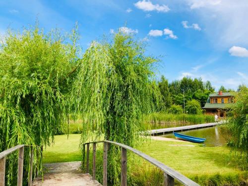 a wooden bridge with a weeping willow tree over a pond at Sielski Dom nad Stawem in Kruklanki