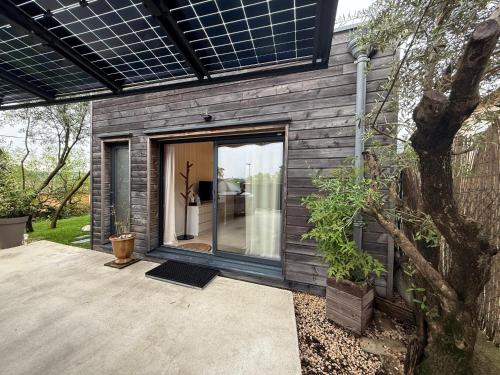 una piccola casa con una porta a vetri su un patio di Lodge Cosy tout confort Lodge des Oliviers a Ganges