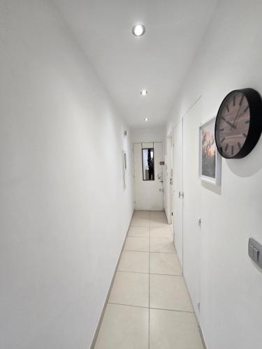 un couloir avec des murs blancs et une horloge sur le mur dans l'établissement Sunny Prom Studio, à Nice