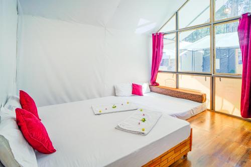 two beds with red pillows in a room with a window at Kabila Camp in Kasol