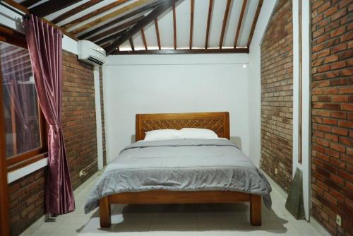 a bed in a room with a brick wall at Joglo Turen Villa in Ngaglik