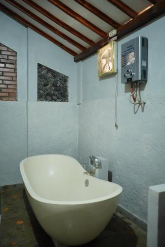 a white bath tub in a bathroom with a tv at Joglo Turen Villa in Ngaglik
