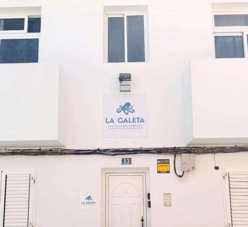 ein weißes Gebäude mit einem Schild mit der Aufschrift „La Cala“ in der Unterkunft La Caleta Holiday Homes in Castillo del Romeral