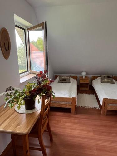 a room with two beds and a table and a window at Dom Między Jeziorami in Świętajno