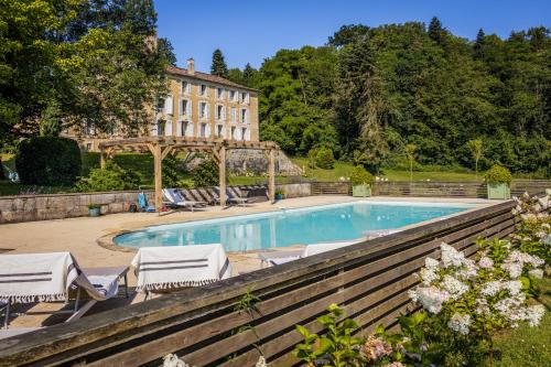 une piscine avec des chaises et un bâtiment en arrière-plan dans l'établissement Chateau de la Guerinchie, beautiful 7 bedroom castle in the heart of the Dordogne, à Thiviers