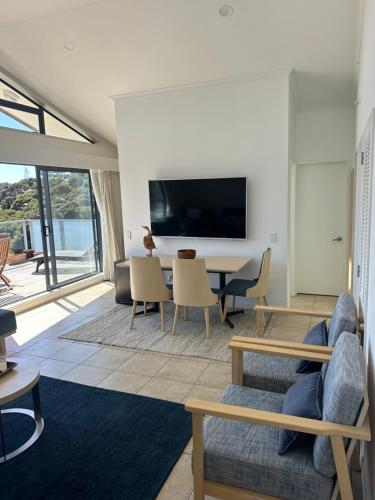 a living room with a tv and a table and chairs at Deluxe Bedroom ldouble or twin bedl in shared Premium Villa at Waiheke Island Resort in Waiheke Island