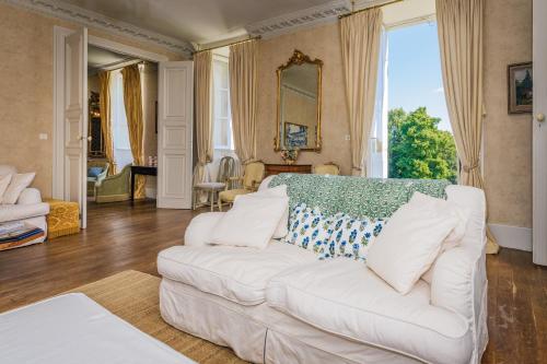 a living room with a white couch and a large window at Chateau de la Guerinchie, beautiful 7 bedroom castle in the heart of the Dordogne in Thiviers