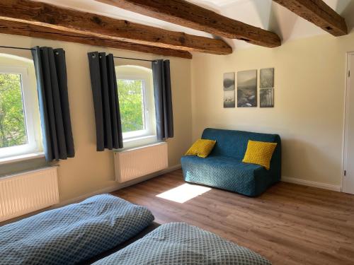 a living room with a blue chair and windows at Ferienwohnung am Rathsburgsee in Gramzow