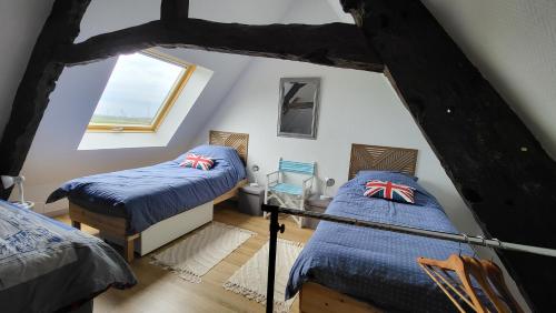 une chambre mansardée avec deux lits et une fenêtre dans l'établissement 17th century house with swimming pool, à Pleurtuit