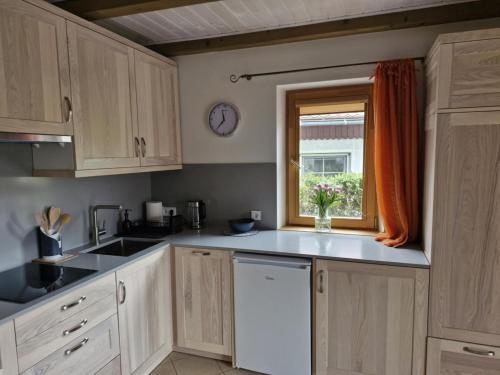 kuchnia z białymi szafkami, oknem i zlewem w obiekcie Jūrena w mieście Nida