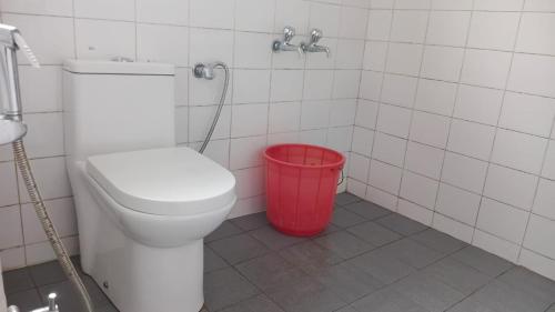 a bathroom with a toilet and a red trash can at Mystical Medows in Ooty