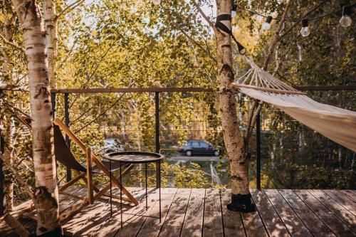 a hammock and a table and chair on a deck at DRZEWOstan in Niechorze