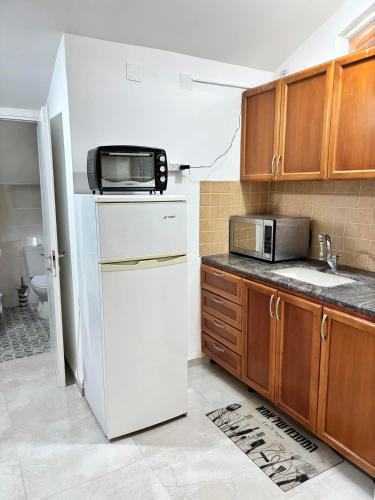 a kitchen with a microwave on top of a refrigerator at אולימפוס in Shelomi