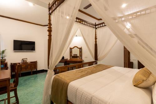 a bedroom with a canopy bed and a television at La Moon Puducherry in Puducherry