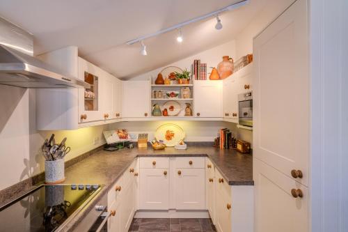 a kitchen with white cabinets and a counter top at Barn Cottage in Broadway