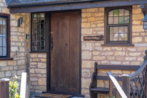 a wooden door on a stone building with a bench at Barn Cottage in Broadway