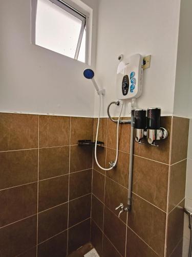 a shower in a bathroom with brown tiles at Serene Homestay in Tawau