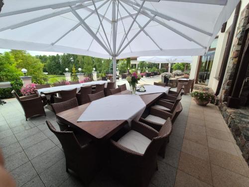a table and chairs under an umbrella on a patio at Villa Romana Mazury in Jeziorowskie