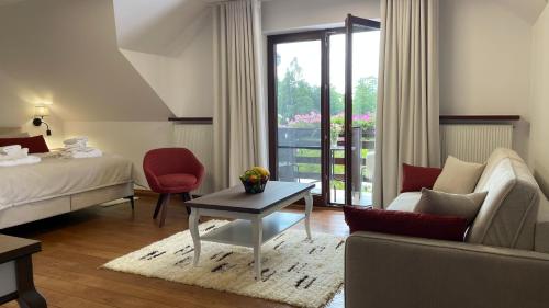 a hotel room with a bed and a couch and a table at Villa Romana Mazury in Jeziorowskie