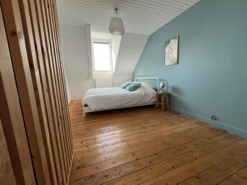 une chambre avec un lit aux murs bleus et au parquet dans l'établissement La maison du port, à Ploudalmézeau
