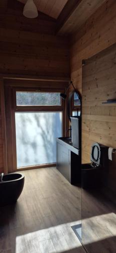 ein Badezimmer mit großem Fenster in einem Holzzimmer in der Unterkunft Chalet au calme in La Bresse