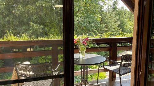 a balcony with a table and chairs and a vase of flowers at Villa Romana Mazury in Jeziorowskie