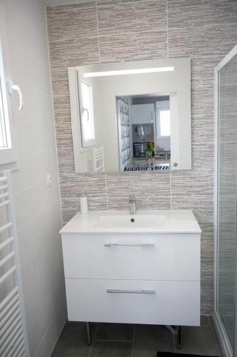 une salle de bain avec un lavabo blanc et un miroir dans l'établissement Maison 4 personnes tout confort à 300m de la plage - Clim & Wifi, à Mimizan-Plage
