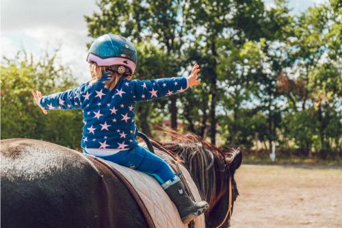 a little girl riding on the back of a horse at Narzissendorf Zloam Hotel in Grundlsee