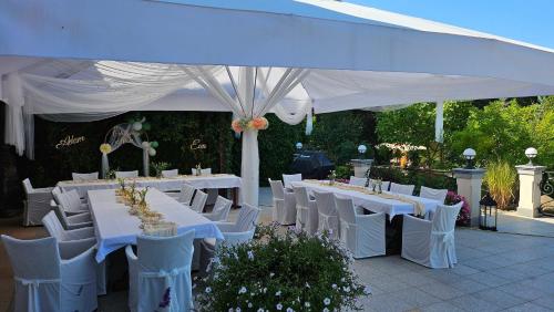 a group of tables and chairs under a white tent at Villa Romana Mazury in Jeziorowskie